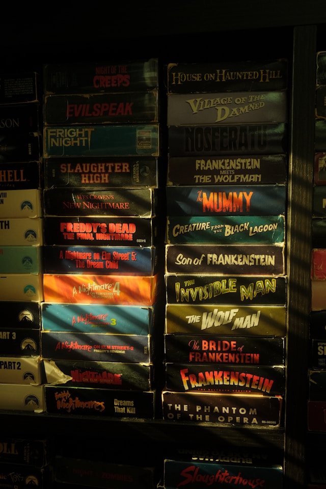 Picture of a bookshelf with stacked VHS horror movies.
